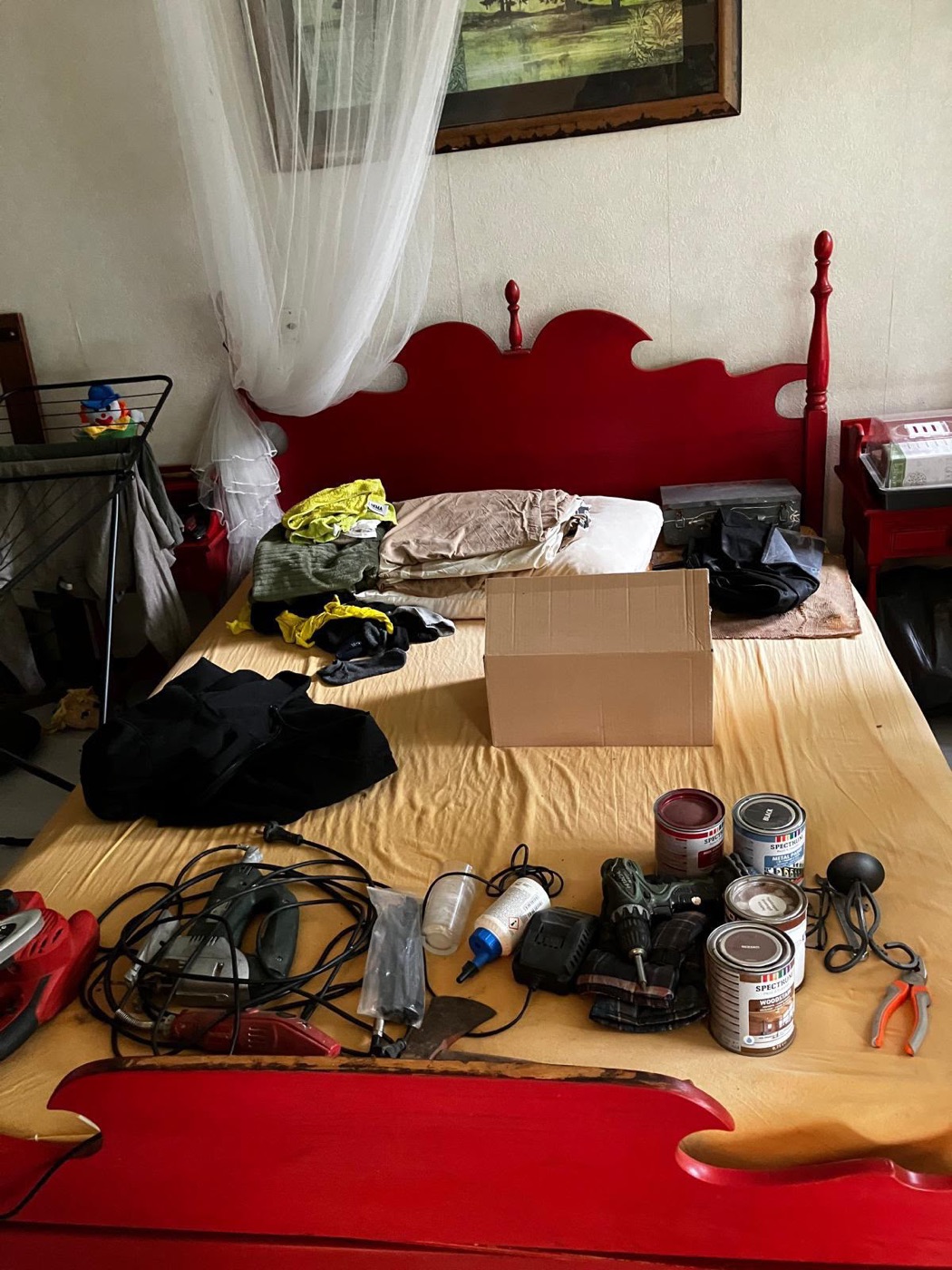 Slaapkamer voor de ontruiming, met spullen en gereedschap op het bed